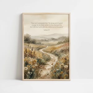 May include: Watercolor print of a landscape with a winding path through fields of wildflowers. The artwork features a soft color palette of beige, brown, and green. Text at the top reads "Have not I commanded thee?" and "Joshua 1:9". The print is framed in a light wood.
