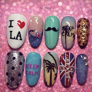 Könnte beinhalten: Ein Set von zehn künstlichen Nägeln mit verschiedenen Designs. Die Designs umfassen den Text "I ❤️ LA", einen Schnurrbart, eine britische Flagge, eine Palme und die Worte "KEEP CALM". Die Nägel sind in verschiedenen Farben lackiert, darunter Weiß, Blau und Silber.