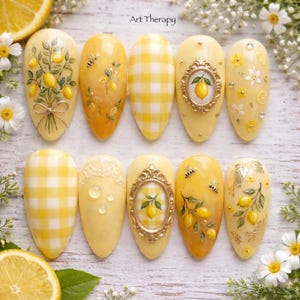 Pode incluir: Um conjunto de dez unhas artificiais amarelas com vários designs. Algumas unhas apresentam ilustrações de ramos de limão, padrões xadrez e arte de limão emoldurada. As unhas são decoradas com pequenos enfeites e o texto "Art Therapy".