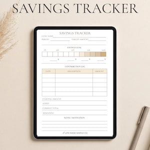 May include: A digital savings tracker displayed on a tablet. The screen shows a detailed form with sections for goal setting, tracking progress, and logging contributions. The text "SAVINGS TRACKER" is at the top. A pen and notebook are on the right.