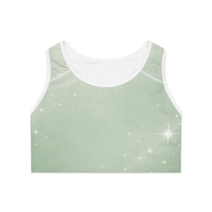 May include: A light green sports bra with a white trim and a white interior. The bra features a sparkling star pattern across the front. The bra is designed for athletic activities.