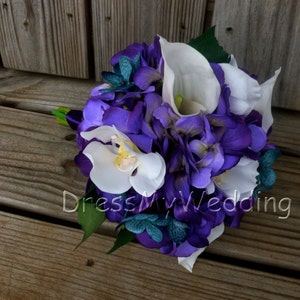 May include: A purple and white bridal bouquet with hydrangeas, calla lilies, and orchids. The bouquet is accented with teal green foliage.