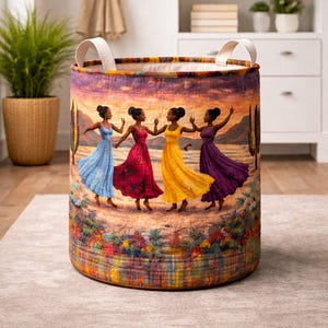 May include: A round storage basket with a colorful illustration of four women in flowing dresses dancing. The dresses are blue, red, yellow, and purple. The basket has white handles and is set on a neutral rug.