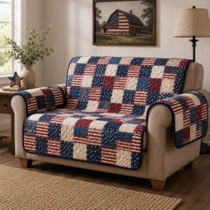 May include: A sofa cover with a patchwork design featuring the American flag in red, white, and blue. The cover is quilted and has a navy blue border. The sofa is beige and has a matching armrest cover.