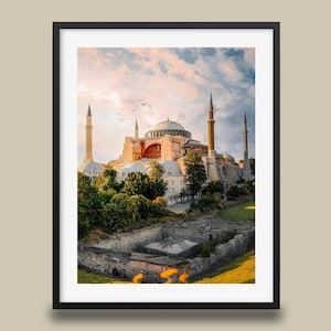 May include: Framed print of the Hagia Sophia in Istanbul, Turkey. The image captures the historic building with its iconic dome and minarets against a sunset sky. The print is encased in a black frame, adding a classic touch to the artwork.