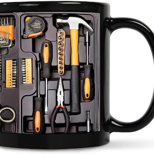 Peut inclure: Mug en céramique noire avec un motif de boîte à outils. Le motif comprend un mètre ruban, un marteau, des tournevis, des pinces et d'autres outils orange et noirs. La tasse a une grande anse incurvée.