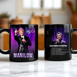 Puede incluir: Taza de cerámica negra con Barry Manilow. Un lado muestra una foto de Manilow con el nombre "MANILOW" debajo. El otro lado enumera las fechas de la gira y el texto "Barry Manilow Farewell Tour". La taza tiene un asa negra.