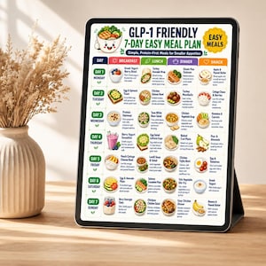 May include: A digital tablet displaying a GLP-1 Friendly 7-Day Easy Meal Plan chart. The grid organizes breakfast, lunch, dinner, and snack options for each day of the week with colorful illustrations of food items and descriptive text labels.