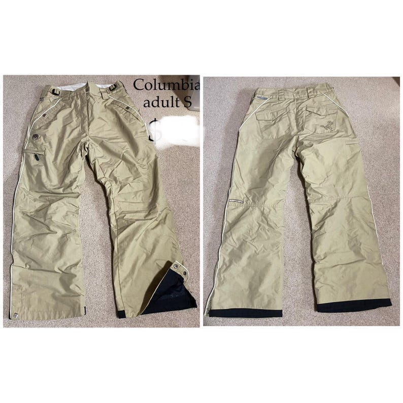 May include: Tan Columbia adult S snow pants. The pants have a straight leg design with white trim along the seams and black accents at the ankles. The front view shows pockets and a zipper closure. The back view shows pockets and a logo.