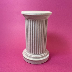 May include: A small, light gray decorative column with a fluted body and a round top and base. The column is set against a bright pink background. The design is reminiscent of classical architecture.