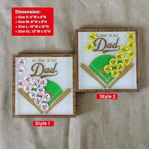 May include: Two wooden framed baseball-themed art pieces. One says "We Caught the Best Dad" with baseballs and a baseball field graphic. The other says "We Caught the Best Dad" with softballs and a softball field graphic. Dimensions are listed.