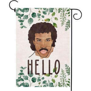 May include: A garden flag featuring a portrait of a man with a mustache and the word "HELLO" in brown letters. The flag is decorated with green leafy vines and a black metal hanging rod.