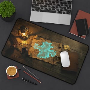 May include: A rectangular desk mat featuring a vintage map with a glowing blue island. The mat includes a compass, gold coins, a lantern, and a laptop, creating a pirate theme. A coffee cup and pencils are also visible.