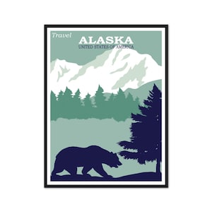 May include: A framed travel poster featuring a dark blue bear silhouette walking past a pine tree in the foreground. The background displays light green rolling hills, a forest of dark green pine trees, and snow-capped white mountains. Text reads Travel ALASKA UNITED STATES OF AMERICA.