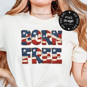 Könnte beinhalten: Cremefarbenes T-Shirt mit dem Schriftzug "BORN FREE" in einem patriotischen Design. Die Buchstaben sind im Stil der amerikanischen Flagge gehalten, mit roten und weißen Streifen und blau gefüllten Sternenabschnitten.