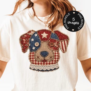 Könnte beinhalten: Cremefarbenes T-Shirt mit einem patriotischen Hunde-Design. Das Gesicht des Hundes besteht aus verschiedenen Stoffen, darunter roter Blumenstoff, blau mit weißen Sternen und Jute. Es hat Knopfaugen und eine Vichy-Nase mit einem Spitzenkragen. Ein kleiner Kreis zeigt "5 Bilder".