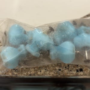 May include: A package of light blue cabinet knobs. The knobs are a soft, rounded shape and appear to be made of a smooth material. The knobs are packaged in a clear plastic bag.