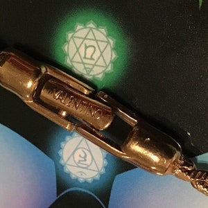 Puede incluir: Primer plano de un cierre de brazalete de cadena dorado con la palabra "VALENTINO" grabada.