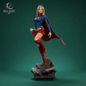 May include: A detailed statue of a superheroine in a dynamic pose. She wears a blue top, red skirt, and boots, with a flowing red cape. The statue is on a rocky base, with the "SCULATIVE" logo visible.