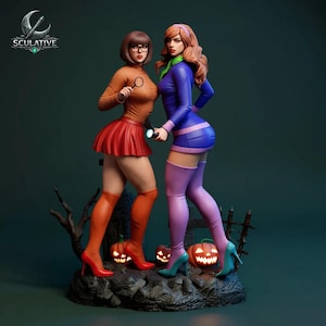 Könnte beinhalten: Eine detaillierte Statue mit zwei Zeichentrickfiguren, eine in einem orangefarbenen Pullover und rotem Rock, die andere in einem blauen Kleid. Sie stehen auf einem felsigen Sockel mit geschnitzten Kürbissen und einem kahlen Baum. Die Statue trägt das Wort "Sculative".