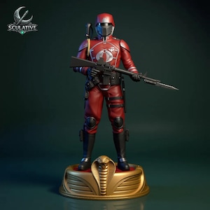 Pode incluir: Figura de ação vermelha de um soldado com uniforme vermelho, capacete e botas pretas, segurando um rifle. A figura está em uma base dourada com um emblema de cobra. A figura é da marca Sculative.