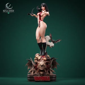 May include: A detailed collectible statue of a female figure with long black hair, wearing a red bodysuit and black boots. The figure stands on a base featuring skulls, a stone cross, and a bat, with the text VAMPIRELLA printed on the front.