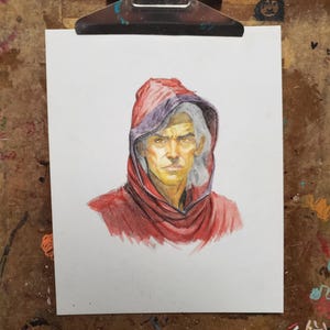 K&ouml;nnte beinhalten: Eine Buntstiftzeichnung auf wei&szlig;em Papier, die das Portr&auml;t einer Person mit hellgrauem Haar in einem dunkelroten Kapuzenumhang zeigt. Die Figur hat einen ernsten Gesichtsausdruck, goldfarbene Haut und ist mittig auf dem Blatt Papier dargestellt.