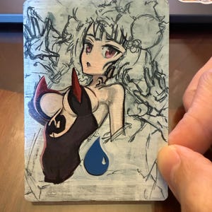 May include: A rectangular trading card featuring a hand-drawn anime-style character with dark hair and red eyes. The character wears a black outfit with red accents and is set against a light gray background with sketch lines and a blue water drop icon.
