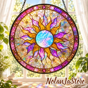 Pode incluir: Um apanhador de sol circular de vitral com um círculo central azul iridescente rodeado por raios radiantes em forma de chama amarelos e roxos. A borda externa é magenta escuro com pequenos detalhes circulares e em forma de estrela.