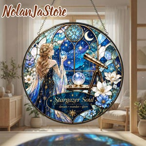 May include: A circular stained glass suncatcher featuring a person with long hair holding a crystal ball, a telescope, and a night sky background. The text reads Stargazer Soul dream wonder glow. The design includes blue and white floral accents.