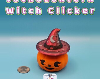 May include: An orange jack-o'-lantern figure wearing a red witch hat with a white crescent moon and star details. The text JackoLantern Witch Clicker appears above. A US penny is placed next to the figure for scale, and a Creatively Cubic logo is below.