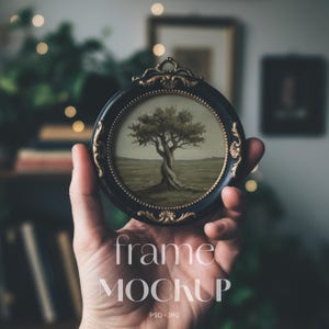 May include: A round, black frame with gold accents, holding a painting of a tree in a field. The frame has ornate detailing and the text "frame MOCKUP" is displayed in white. The image is a PSD-JPG file.