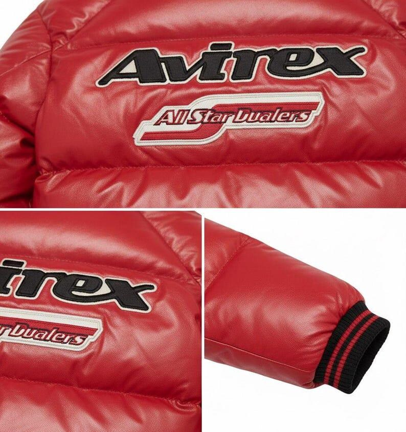 May include: A close-up of a red jacket with the brand name "Avirex" embroidered in black and white. Below the brand name is the text "All Star Dualers". The jacket has a quilted design and a black and red striped cuff.
