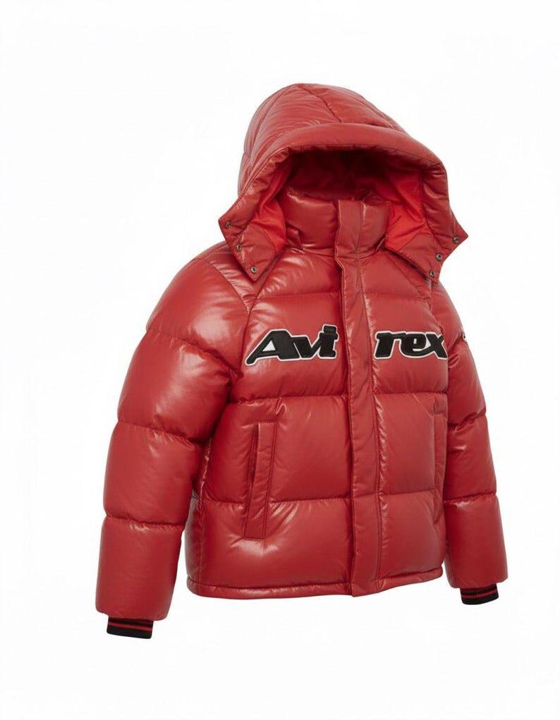 May include: A red puffer jacket with a hood. The jacket has the text "Avi Rex" in black and white on the chest. The jacket has a glossy finish and a black and red striped cuff.