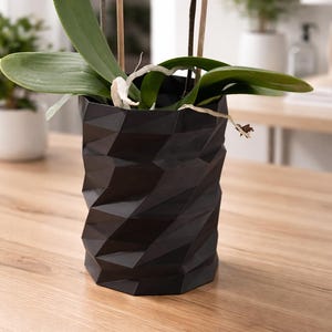 May include: A white ceramic mug with a black handle and the text "But First, Coffee" in a bold, black font. The mug is set against a neutral background, highlighting its simple design.