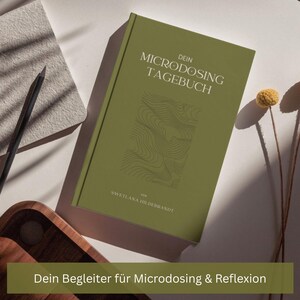 Puede incluir: Un diario de tapa dura verde titulado "DEIN MICRODOSING TAGEBUCH" con un diseño topográfico. El nombre de la autora, Swetlana Hildebrandt, está impreso en la parte inferior. Un lápiz y un bloc de notas son visibles en el fondo.