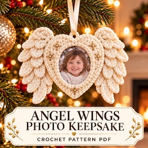 Può includere: Un ornamento a forma di cuore per cornice portafoto, realizzato all'uncinetto color crema, con ali d'angelo testurizzate su entrambi i lati e piccoli dettagli a stella dorati. La cornice contiene la foto di un bambino sorridente e pende da un nastro di raso.
