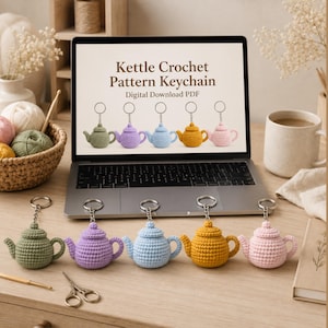 Puede incluir: Una pantalla de portátil muestra el texto Kettle Crochet Pattern Keychain Digital Download PDF sobre cinco pequeños llaveros de tetera de ganchillo en verde oliva, lavanda, azul claro, amarillo mostaza y rosa suave, con llaveros iguales debajo.