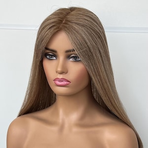 Könnte beinhalten: Ein Schaufensterpuppenkopf mit langem, glattem, hellbraunem Haar mit dezenten Highlights. Das Haar ist in der Mitte gescheitelt und fällt über die Schultern. Die Puppe hat einen neutralen Gesichtsausdruck mit bemalten Augen und rosa Lippen.