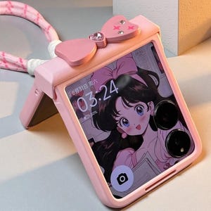May include: A pink phone case featuring a bow detail and a strap. The phone screen shows an anime character with black hair and blue eyes. The time displayed on the screen is 03:24.