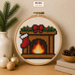 Peut inclure: Un mini motif de point de croix dans un tambour à broder en bois mesurant 5,08 cm sur 5,08 cm. Le motif représente une cheminée marron avec une flamme jaune et orange vive, une chaussette de Noël rouge et une guirlande verte à baies rouges.