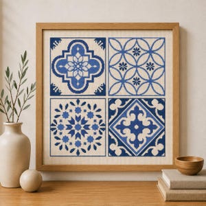 May include: A square cross-stitch embroidery piece framed in light wood, featuring four distinct blue and cream geometric tile patterns arranged in a grid. The design displays intricate floral and star-like motifs rendered in shades of blue.