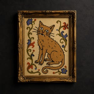 Könnte beinhalten: Eine Kreuzstichstickerei einer beigefarbenen Katze mit sichtbaren Fangzähnen auf beigem Stoffgrund. Die Katze ist von grünen Ranken mit blauen und roten Blumenakzenten umgeben. Das Werk befindet sich in einem verzierten, goldfarbenen Rahmen.