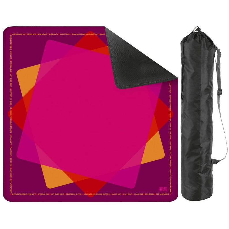 May include: A magenta yoga mat with overlapping geometric shapes in orange, red, and pink. The mat has a dark purple border with white text. A black carrying bag with a shoulder strap is next to the mat.