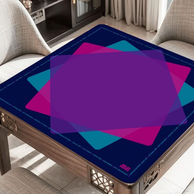 May include: A square table with a dark blue surface featuring overlapping geometric shapes in purple, teal, and pink. The table has a wooden frame and is surrounded by two chairs. The design includes text along the edge.