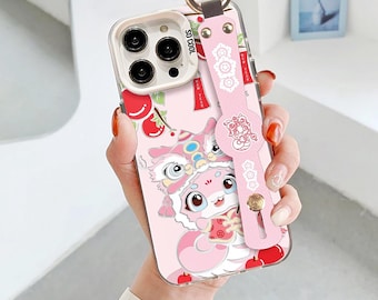 Könnte beinhalten: Eine rosa Handyhülle mit einem Cartoon-Löwentanz-Design, mit einem passenden rosa Riemen mit einem goldenen Ring. Die Hülle hat den Text "SO COOL" und ist mit roten Kirschen verziert.