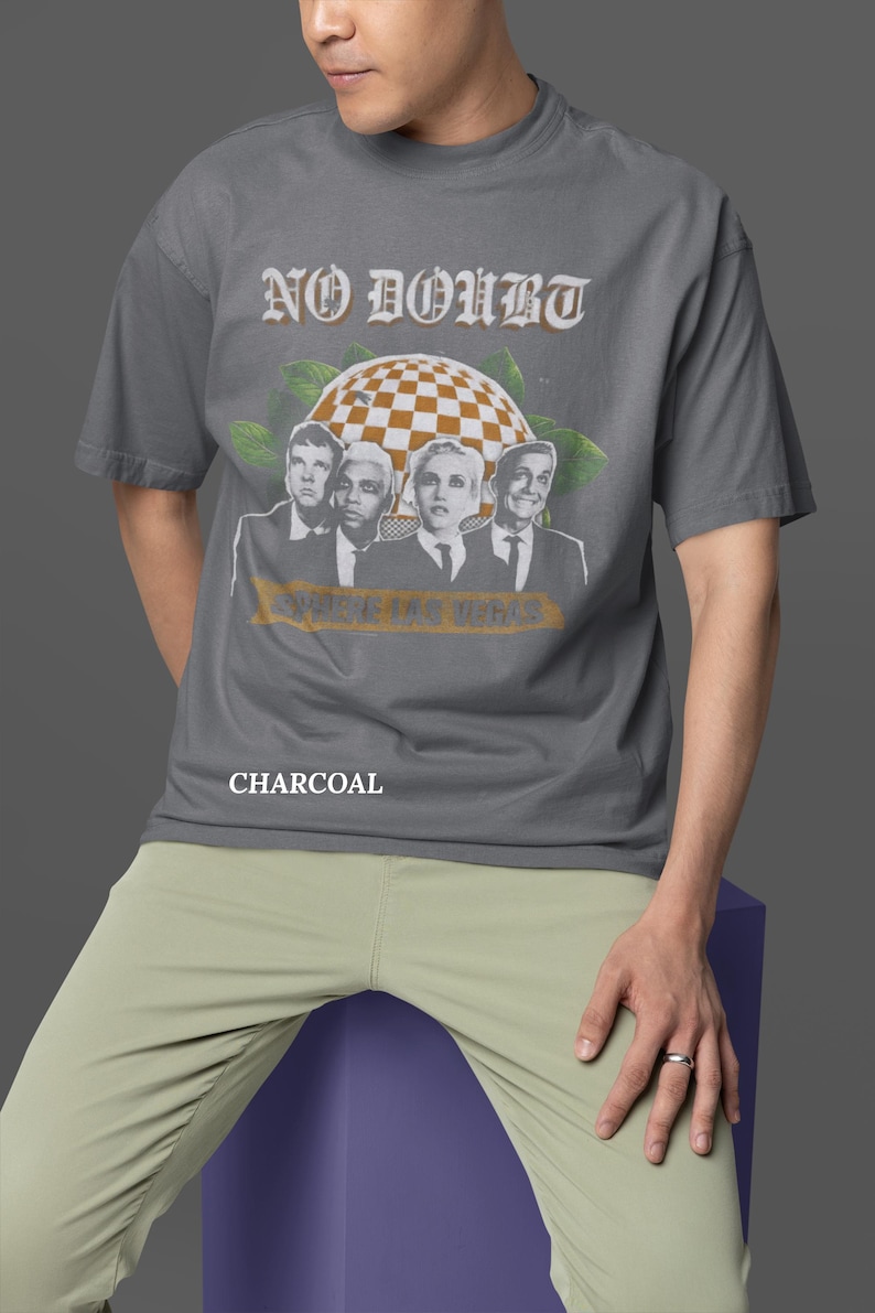 May include: Charcoal gray t-shirt featuring the band No Doubt with a graphic of the band members and the text "SHOWS IN LAS VEGAS". The shirt is a short-sleeved, crew neck style.