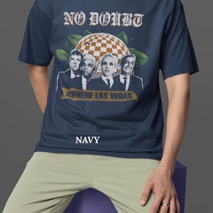 May include: Navy blue t-shirt featuring the band No Doubt with the text "NO DOUBT" in a vintage font. The shirt has a graphic of the band members and the text "SPHERE LAS VEGAS". The word "NAVY" is printed at the bottom.