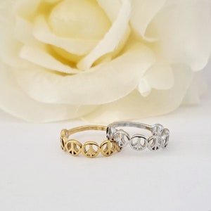 May include: Two peace sign rings, one gold and one silver, on a white background.