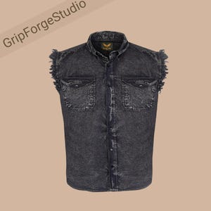 May include: A sleeveless denim vest in a dark charcoal acid wash finish. The garment features a standard collar, a front button-down closure, and two chest pockets with buttoned flaps. The armholes have a frayed, raw-edge design detail.